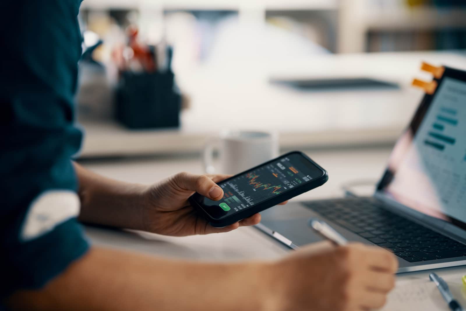 man checking financial information on a smart phone while doing his bookkeeping